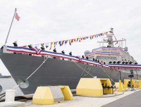 A decorated Navy ship alongside a pier