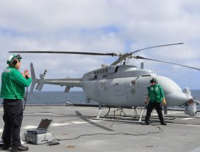 Unmanned Navy helicopter on a flight deck with two crew members