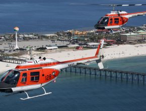 two helicopters flying over a beach