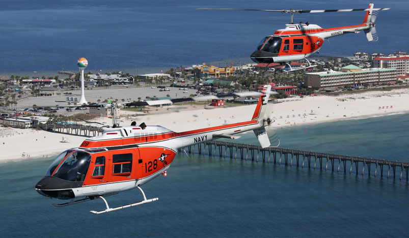 two helicopters flying over a beach