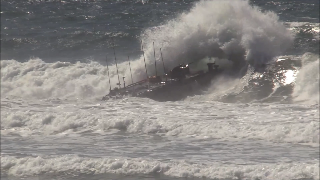 An amphibious vehicle crashes into a wave in high ocean surf
