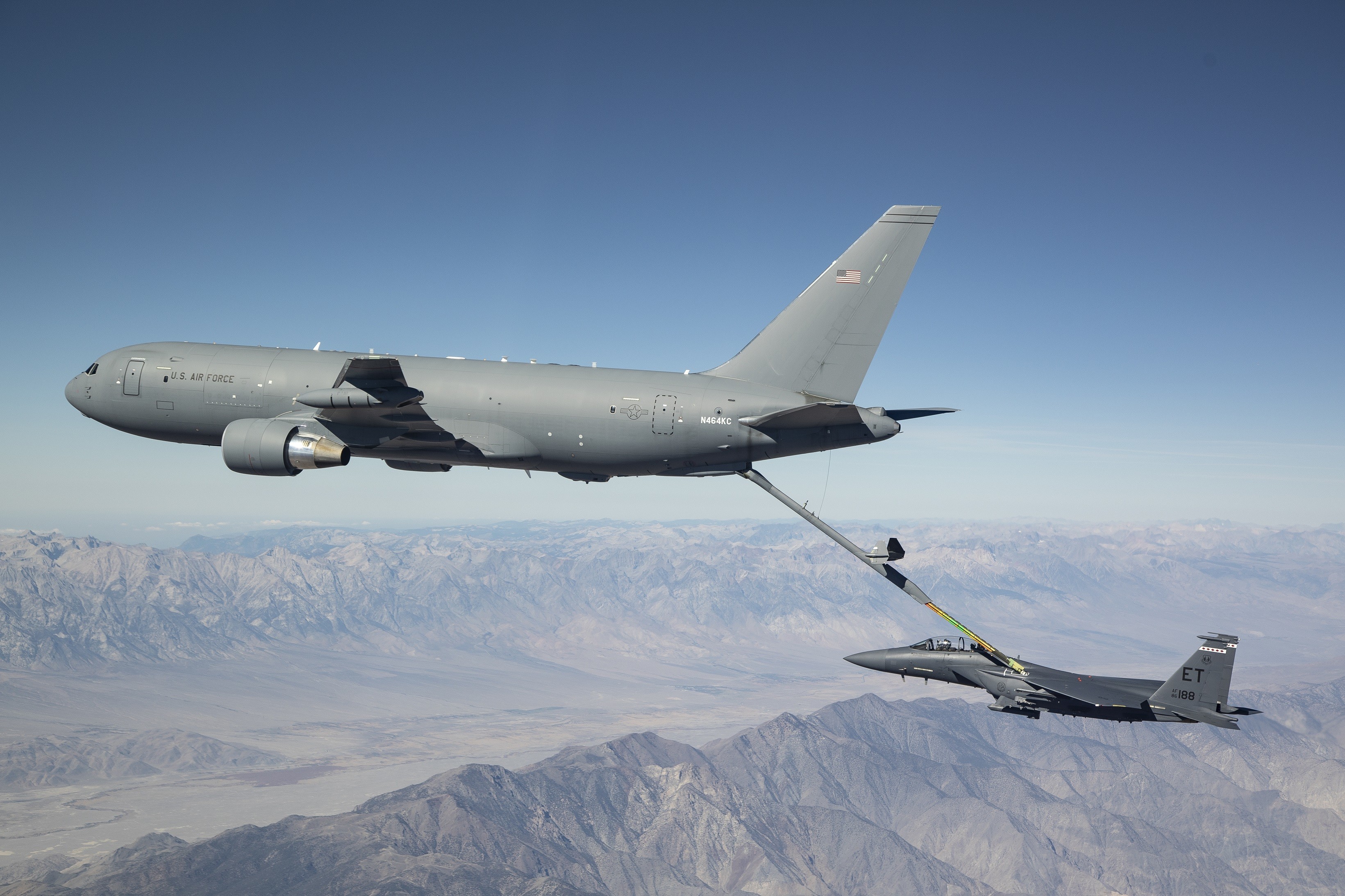 aerial tanker refueling a fighter jet above the mountains