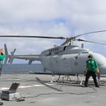 Unmanned Navy helicopter on a flight deck with two crew members