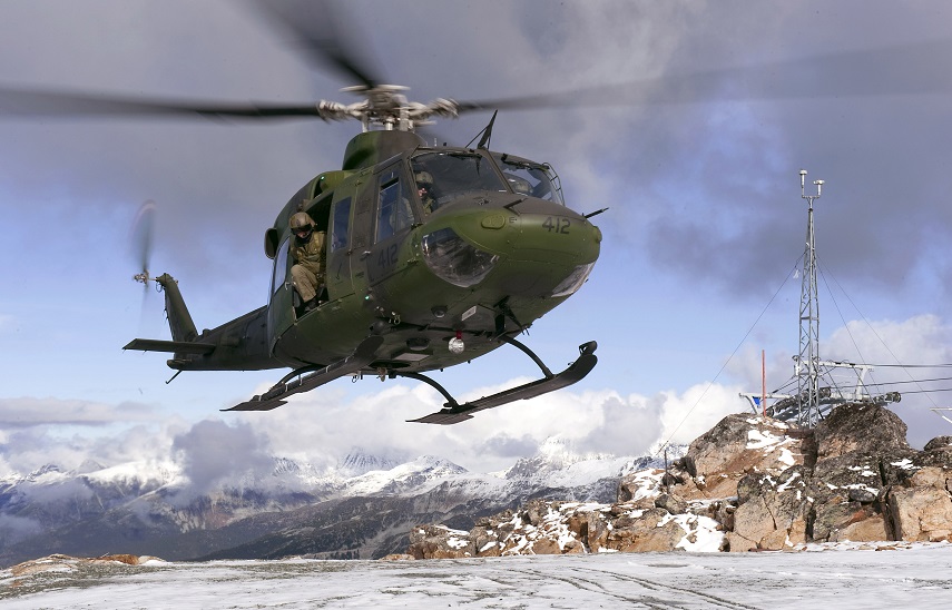 A Canadian helicopter flying in the snowy mountains