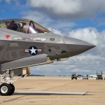 fighter pilot inside the canopy of a jet sitting on tarmac