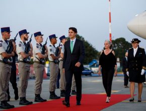 justin trudeau walks on a red carpet in front of a military guard