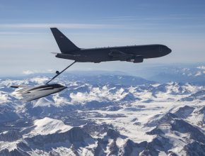 a bomber aircraft is refueled midair above snow-capped mountains
