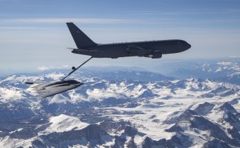 a bomber aircraft is refueled midair above snow-capped mountains