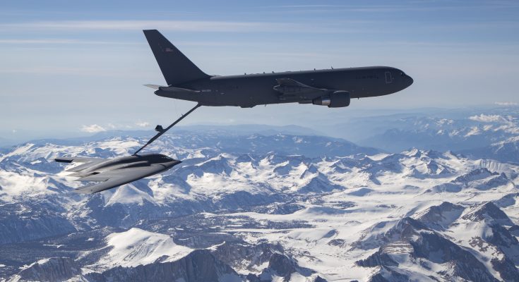 a bomber aircraft is refueled midair above snow-capped mountains