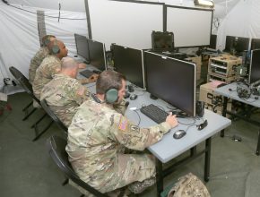 Soldiers working on computers in a tent