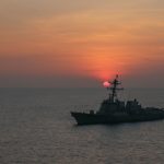 A u.s. navy warship sails at sunset