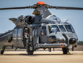 a military helicopter sits on a runway