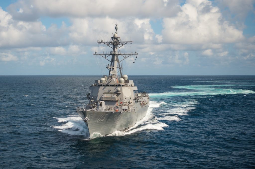 U.S. Navy warship sails in blue water on a cloudy day