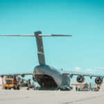 a military cargo plane sits on the tarmac being loaded with equiment