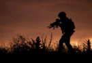 Silhouette of a soldier walking through the grass at sunset