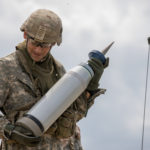A soldier carries a tank round