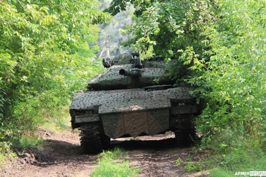 a combat vehicle drives through a forest