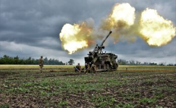 flames erupt from the barrel of a howitzer being fired in a field