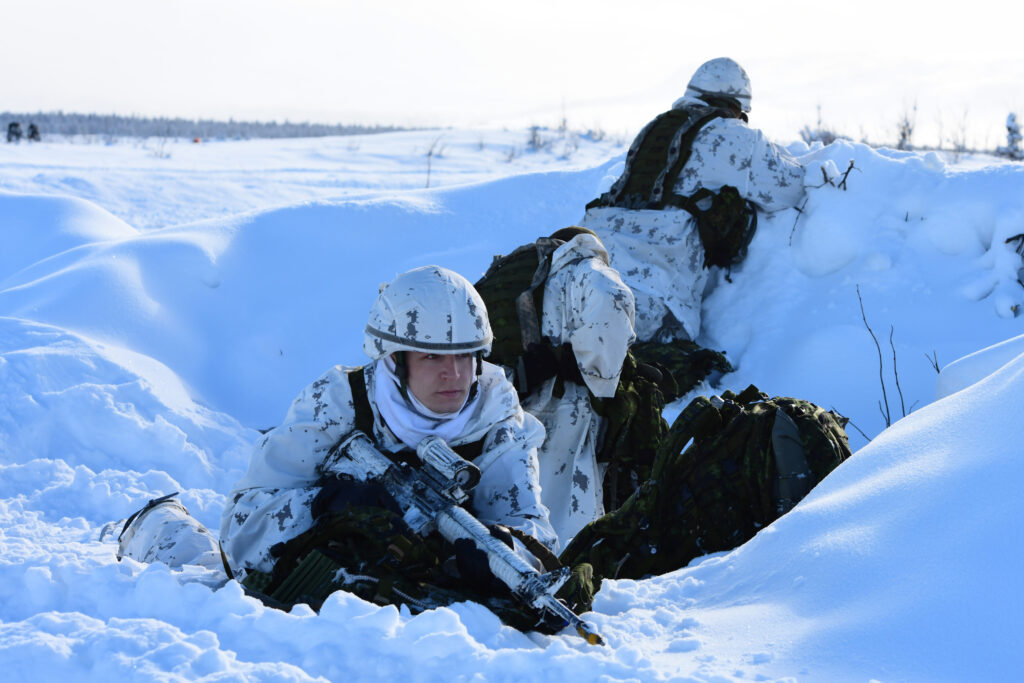 soldiers dressed in winter gear take cover in the snow