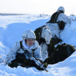 soldiers dressed in winter gear take cover in the snow