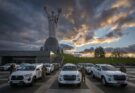 soldiers stand next to pickup trucks as the sun sets