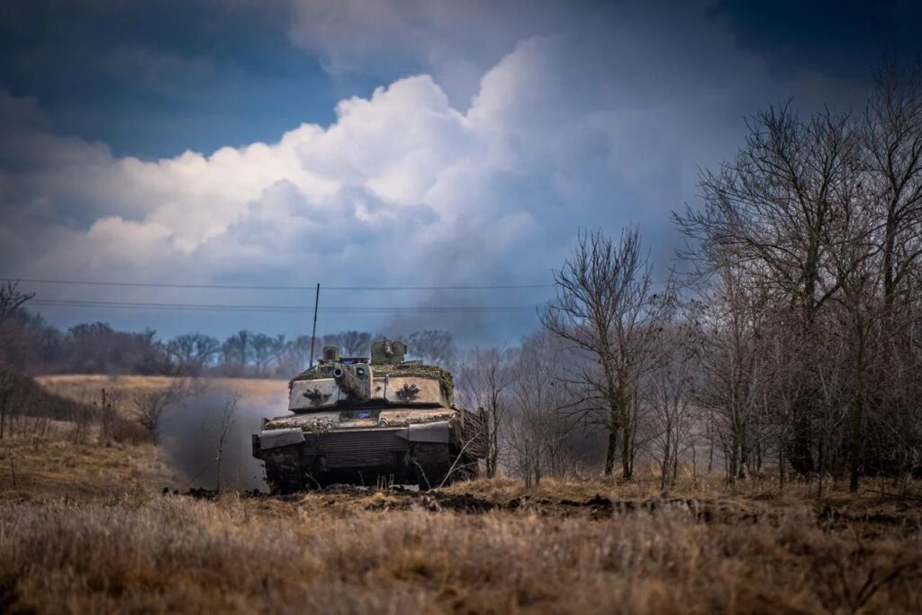 A tank donated by Britain drives through a field in Ukraine 