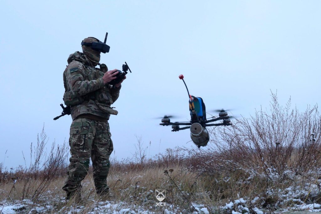 a soldier operates a small quadcopter drone carrying an explosive 