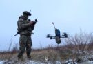 a soldier operates a small quadcopter drone carrying an explosive