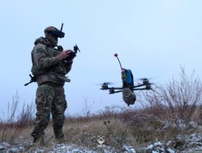 a soldier operates a small quadcopter drone carrying an explosive