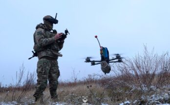 a soldier operates a small quadcopter drone carrying an explosive