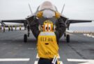 A fighter jet receives instructions on the flight deck