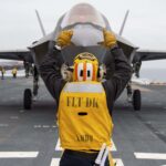 A fighter jet receives instructions on the flight deck