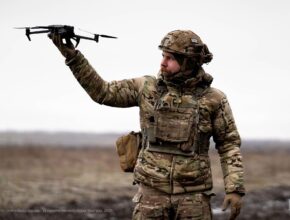 a soldier holds up a small drone