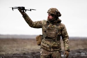 a soldier holds up a small drone