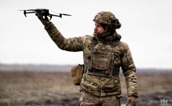 a soldier holds up a small drone