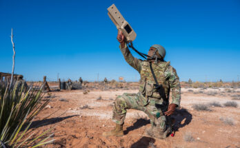 a kneeling soldier aims a counter-drone system towards the sky