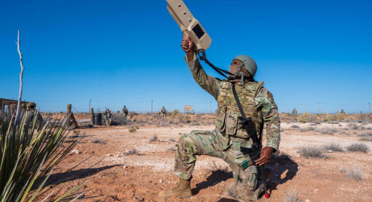 a kneeling soldier aims a counter-drone system towards the sky