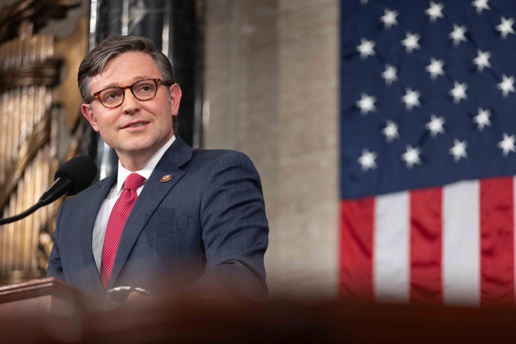 The Speaker of the House stands in front of an American flag