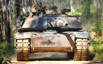 A tank drives down a dirt path in a forest