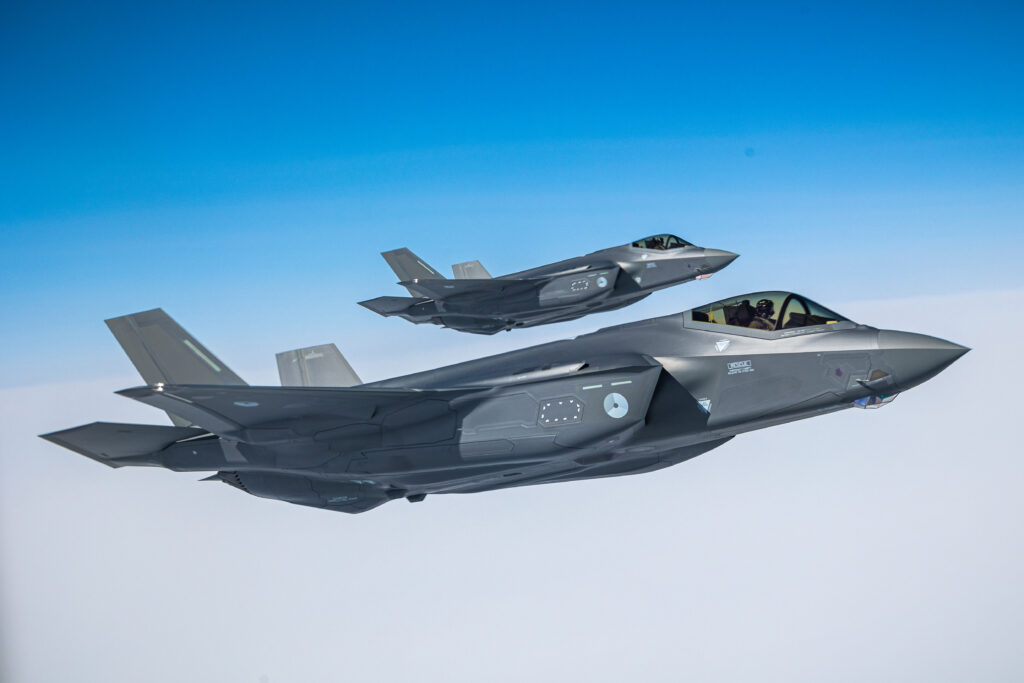 A pair of fighter jets fly above the clouds