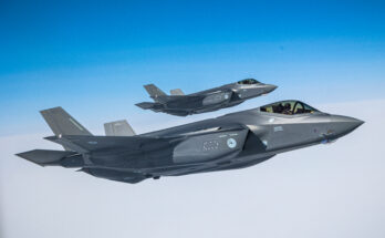 A pair of fighter jets fly above the clouds