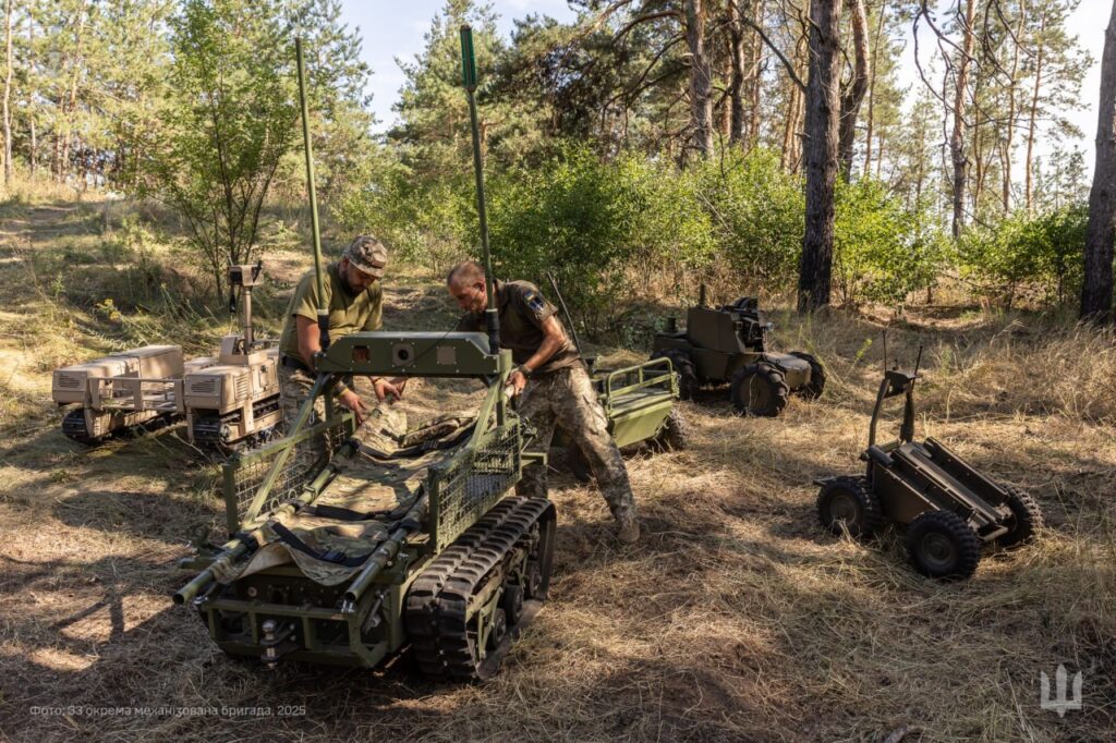 Soldiers work with unmanned ground vehicles in a forest