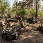 Soldiers work with unmanned ground vehicles in a forest