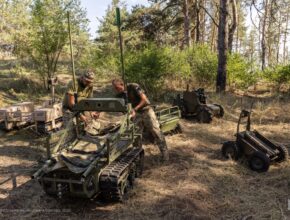 Soldiers work with unmanned ground vehicles in a forest