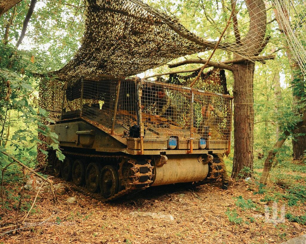An armored vehicle hides in a forest.