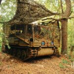 An armored vehicle hides in a forest.