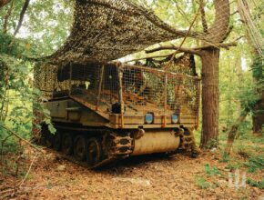 An armored vehicle hides in a forest.
