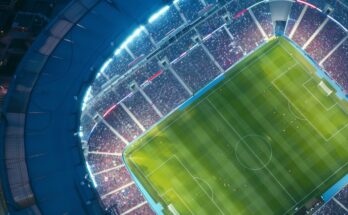 Aerial drone view of modern football soccer pitch sports stadium ground at night lights