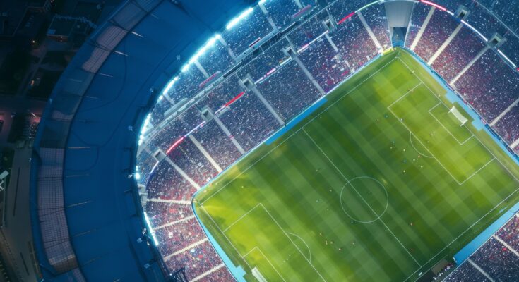 Aerial drone view of modern football soccer pitch sports stadium ground at night lights